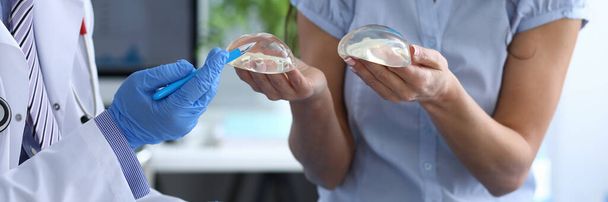 Patient holds breast implants next to doctor - Fotoğraf, Görsel