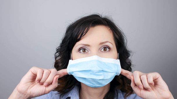 Женщина в защитной маске против коронавируса. Женщина в маске. Не могу дышать. Снимаю маску для лица пальцами. Медицинская маска, Закрытый снимок, Выберите фокус, Предотвращение от covid19 - Фото, изображение