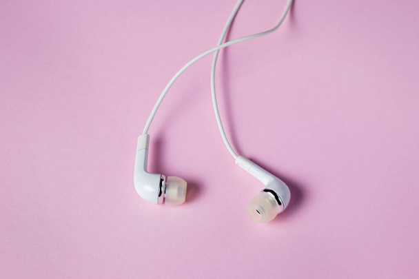 Witte koptelefoon op een roze achtergrond. Muzikaal accessoire. Moderne gadget - Foto, afbeelding