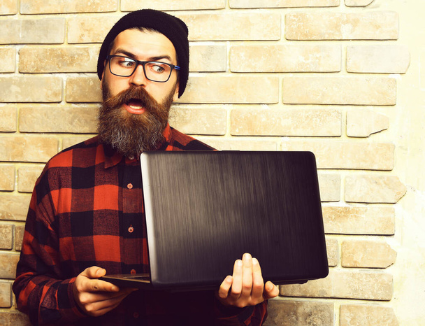 Bearded brutal caucasian hipster holding laptop - Foto, imagen