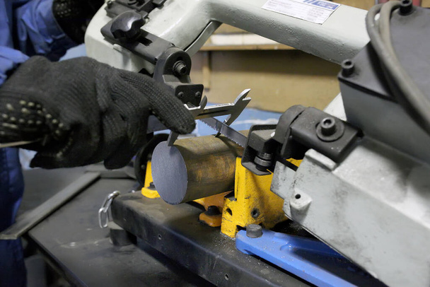 Bandsäge. Ein Arbeiter misst die Größe einer Eisenscheibe mit einem Bremssattel - Foto, Bild