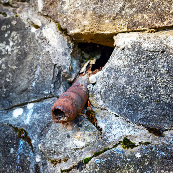 Una vieja tubería oxidada sobresale de una pared de piedra. La impotencia, las enfermedades genitales en los hombres concepto. El tubo parece un viejo pene dolorido.
. - Foto, Imagen
