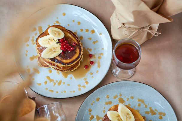 Fresh homemade pancakes with red currants and caramel on gray plate and craft background with black and strong coffee. Delicious breakfast and pastries. - Foto, Bild