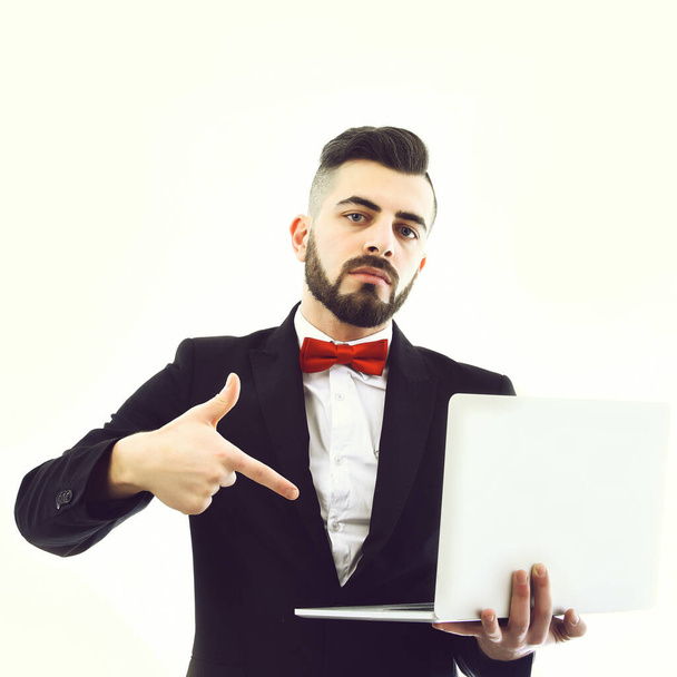 Successful businessman with beard and serious face points at laptop - Φωτογραφία, εικόνα