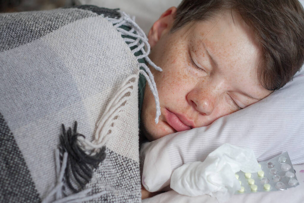 Ώριμη μελαχρινή γυναίκα κοιμάται στο κρεβάτι της κάτω από καρό κουβέρτα, έννοια της ασθένειας ή του κρύου, θεραπεία στο σπίτι, επιλεκτική εστίαση - Φωτογραφία, εικόνα