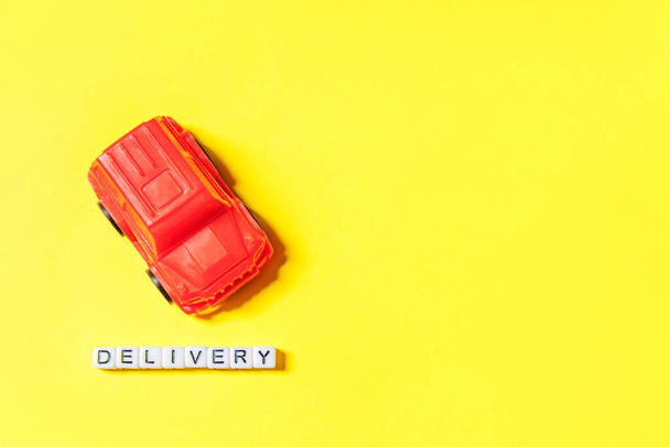 Wystarczy zaprojektować czerwony samochód zabawki i napis DOSTAWA słowo izolowane na żółtym tle kolorowe. Zakupy internetowe zakup online e-commerce pakiety koncepcja usługi dostawy. Przestrzeń kopiowania - Zdjęcie, obraz