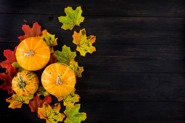 Decorative Mini pumpkins with fall dried leaves on dark old wooden background, autumn concept or fall holiday, Thanksgiving Day, copy space - Fotoğraf, Görsel