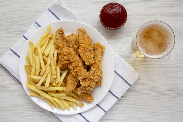 Homemade Crispy Chicken Tenders and French Fries with sauce and glass of cold beer, overhead view. Top view, from above, flat lay. - Фото, изображение