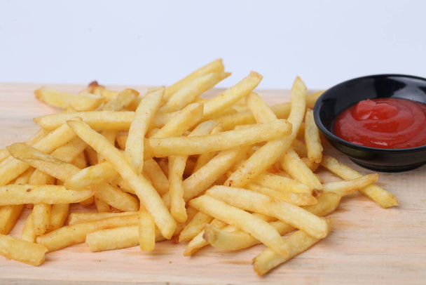 Tasty french fries or kentang goreng on cutting board, on wooden table background isolated on white - Photo, Image