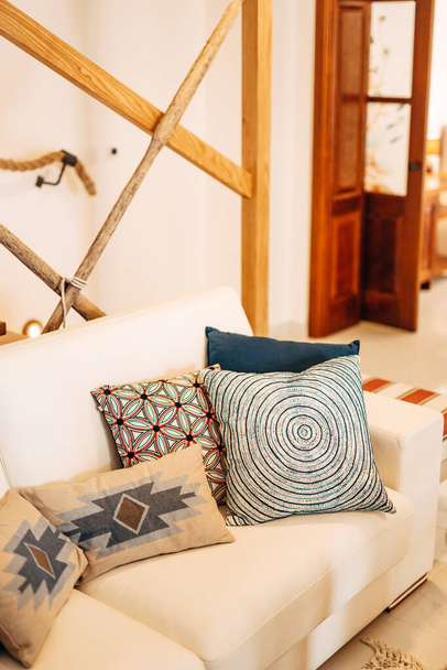 Travesseiros de diferentes cores e tamanhos em um sofá branco em uma sala brilhante. - Foto, Imagem