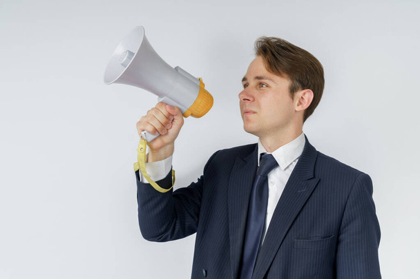 A businessman speaks into a loudspeaker. White background. Business and finance concept - Foto, Imagem