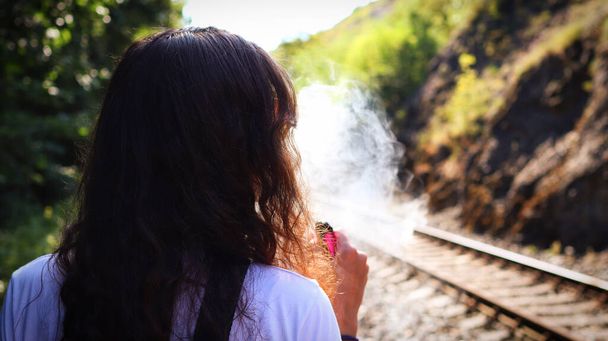 Fiatal nő elpárolog egy elektronikus cigaretta és kilélegzi a füst. - Fotó, kép