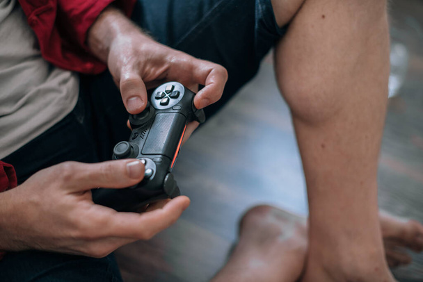 Close-up of male hands with a joystick. Man playing video game while sitting on the floor - Photo, Image