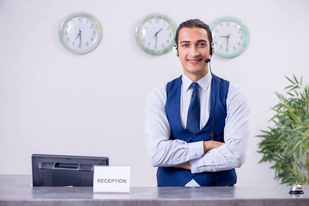 Young man receptionist at the hotel counter - Fotó, kép