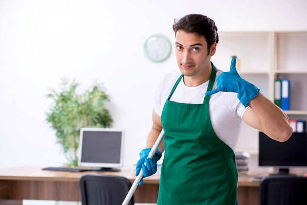 Young handsome contractor cleaning the office - Foto, Bild
