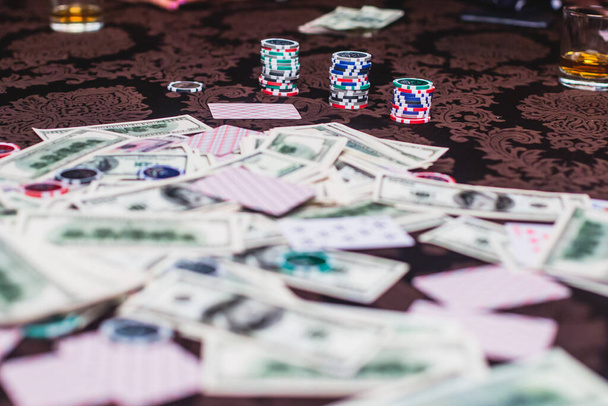 View of poker table with pack of cards, tokens, alcohol drinks, dollar money and group of gambling rich wealthy people playing poker - Foto, Imagen