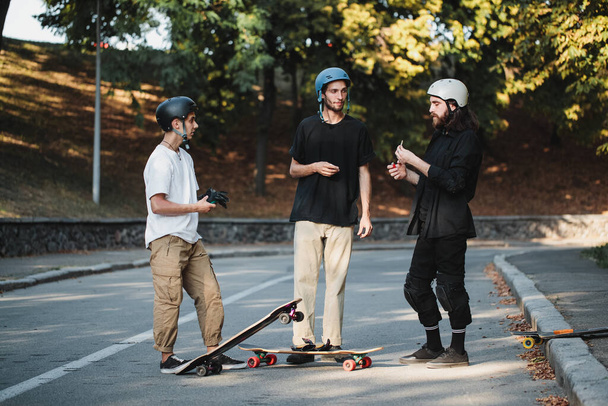 Three guys talk about skateboarding. - Photo, Image