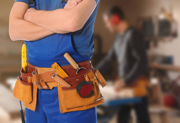 Carpenter with tool belt in workshop, closeup - Zdjęcie, obraz