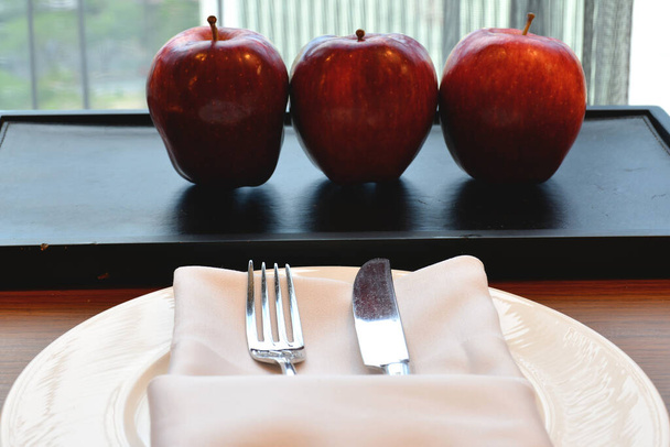 Manzanas maduras de cortesía con cuchillo, tenedor, servilleta de tela y uso de plato para comer cuando tiene hambre - Foto, Imagen