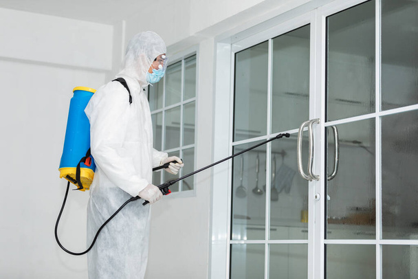 Καθαρισμός και απολύμανση στην πόρτα του μαγειρείου εν μέσω της επιδημίας του coronavirus Επαγγελματικές ομάδες για προσπάθειες απολύμανσης Πρόληψη και έλεγχος επιδημιών Προστατευτική στολή και μάσκα. - Φωτογραφία, εικόνα