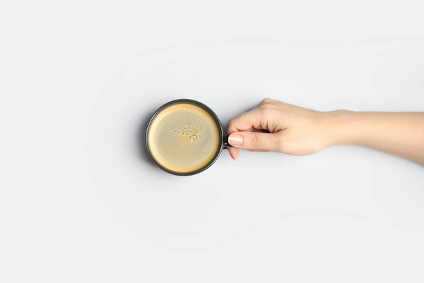 Woman with cup of coffee on light background, top view - Foto, Bild