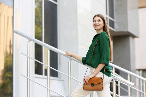 Beautiful young woman with stylish leather bag outdoors on summer day - Foto, imagen