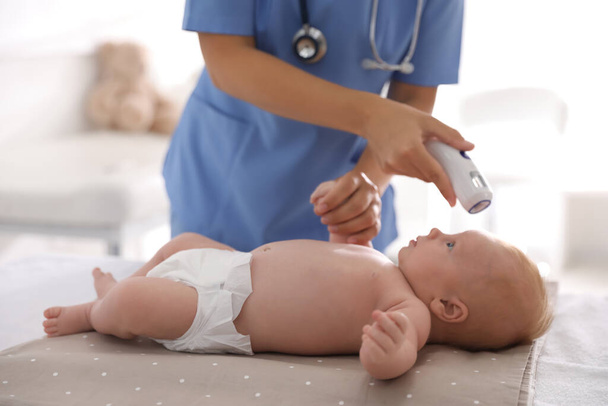 Doctor measuring temperature of little baby with non-contact thermometer in clinic, closeup. Health care - Foto, afbeelding