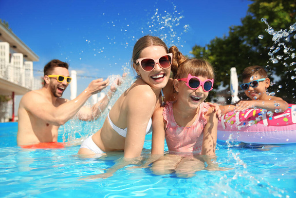 Happy family having fun in swimming pool - Foto, afbeelding