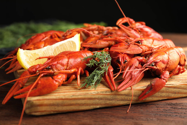 Delicious boiled crayfishes with lemon and dill on wooden table, closeup - Valokuva, kuva