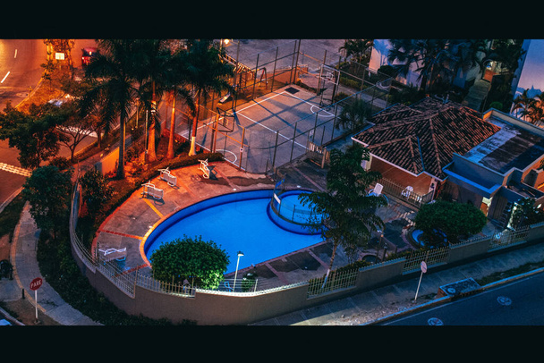 casa com piscina e palmeiras à noite
 - Foto, Imagem