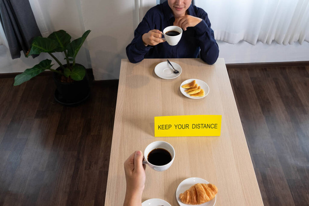 Καθισμένος και τρώγοντας καφέ και σνακ που κρατούν απόσταση - Φωτογραφία, εικόνα