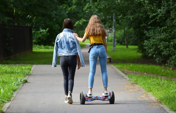 A girl teaches her friend to ride a gyro scooter, prospekt Bolshevikov, Saint Petersburg, Russia August 2020 - Foto, Imagen