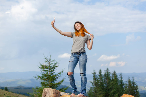 girl takes a selfie on a smartphone in the carpathians on a cloudy sunny summer day - Foto, Bild