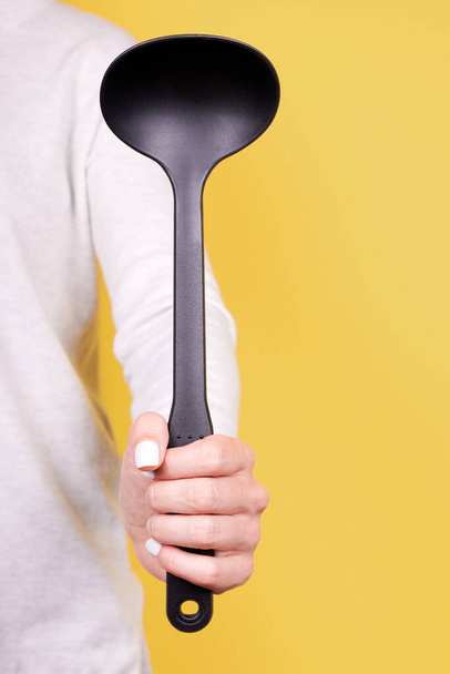 Black plasic ladle in hand. - Photo, image