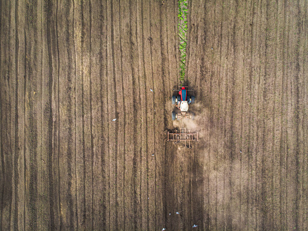 A large agricultural machine cultivates the land. The view from the top. Plowing land for planting crops. photos from the bird's eye view with a quadcopter - Photo, Image