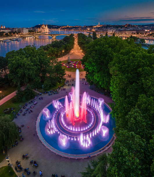 Budapest, Hongrie - Vue aérienne de la fontaine musicale de Margaret Island au crépuscule avec le bâtiment du Parlement, le bastion des pêcheurs et le château royal de Buda en arrière-plan - Photo, image