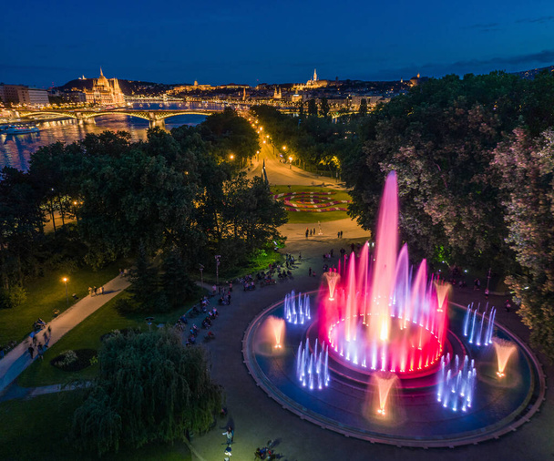 Budapest, Hungary - Aerial view of the Margaret Island Musical Fountain at dusk with Parliament building, Fisherman's Bastion and Buda Castle Royal Palace at background - Photo, Image