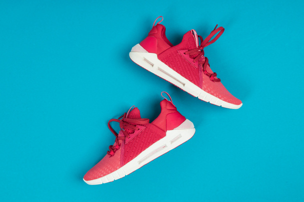 Par de zapatillas nuevas de color rosa, zapatos deportivos sobre fondo azul. Rosa mujer deporte, zapatillas de running - Foto, Imagen
