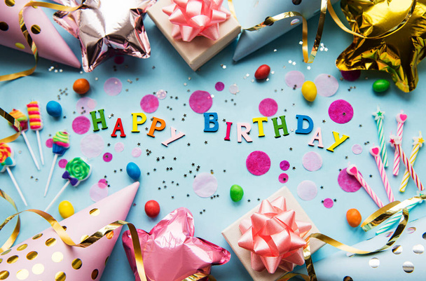 Tekst Gelukkige Verjaardag met houten letters met verjaardagsartikelen, kaarsen en confetti op blauwe achtergrond - Foto, afbeelding