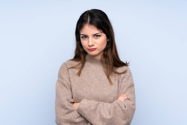 Junge brünette Frau, die einen Pullover über einem isolierten blauen Hintergrund trägt, ist aufgebracht - Foto, Bild