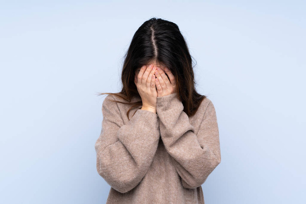 Giovane donna bruna indossa un maglione su sfondo blu isolato con espressione stanca e malata - Foto, immagini