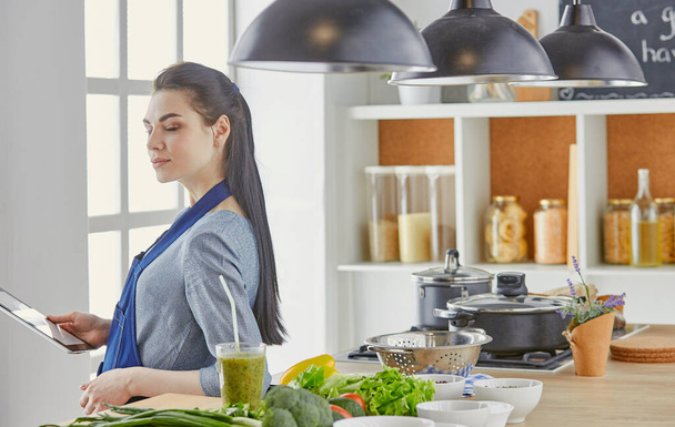Onnellinen nainen etsii resepti tabletti keittiö käsittelyssä ruoanlaitto - Valokuva, kuva