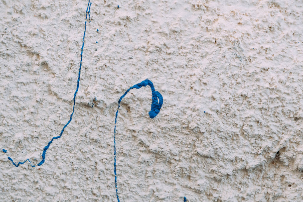 Grungy kuvioitu valkoinen maalaus seinään kaksi tilkka sinistä maalia lähikuva. Seinärakenne tausta. - Valokuva, kuva