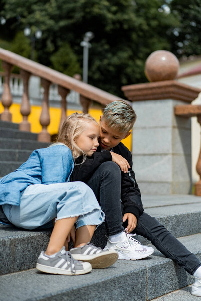 Two happy children, brother and sister, sibling interaction. Brother and sister dressed in casual on the steps in the city center. - Foto, imagen