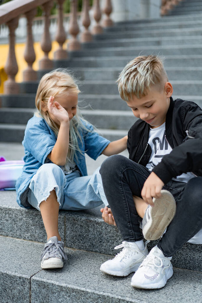 Two happy children, brother and sister, sibling interaction. Brother and sister dressed in casual on the steps in the city center. - Foto, imagen