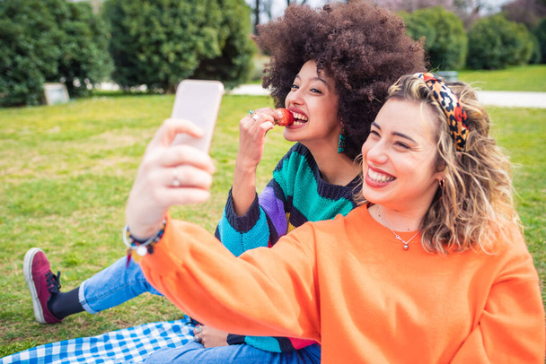Dos amigas al aire libre tomando selie divertirse - friedns masculinos riendo con smartphone - tecnología, felicidad, concepto sociable - Foto, imagen