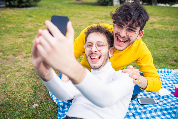 Deux hommes amis en plein air prendre selie avoir du plaisir - Friedns masculins riant en utilisant smartphone - technologie, bonheur, concept sociable - Photo, image