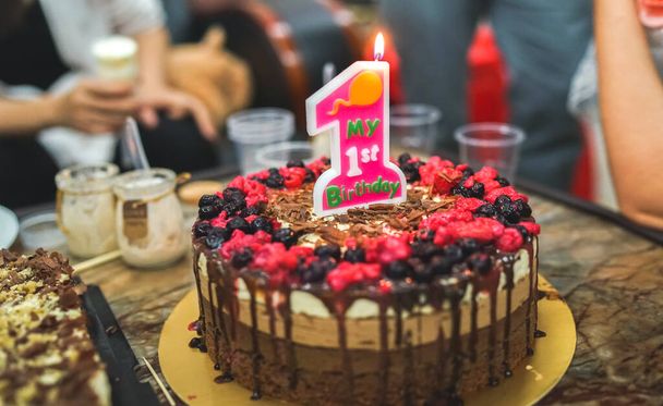 My first birthday cake, chocolate cake decorated with fresh berries, home birthday party, homemade cake with a lit candle  - Foto, Bild