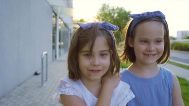 dos niñas lindas están caminando por las calles de la ciudad al atardecer - Metraje, vídeo