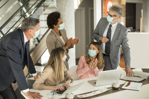 Група бізнесменів зустрічаються і працюють в офісі і носять маски як захист від коронавірусу
 - Фото, зображення